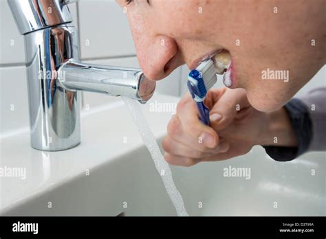 Woman Is Brushing Her Teeth While Water Is Still Running From The Tap