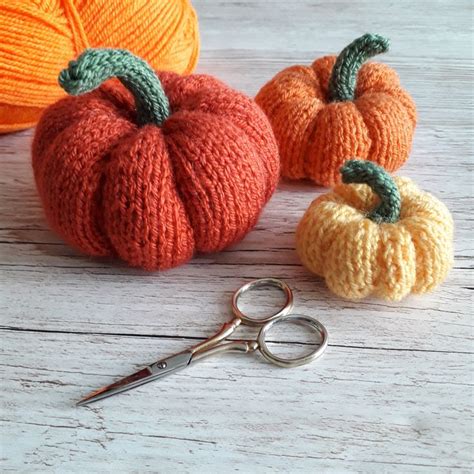 Three Knitted Pumpkins Sitting Next To Each Other On A Wooden Table