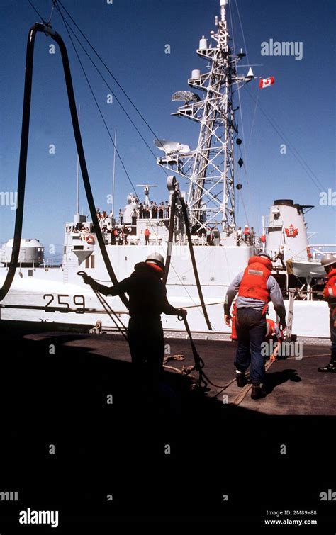 Crew Members Retrieve A Refueling Hose Aboard The Battleship Uss