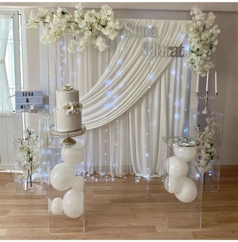 A White Wedding Cake Sitting On Top Of A Table Next To Tall Vases