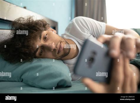 Handsome Young Arab Man In Pajamas Uses A Cellphone While Lying In Bed