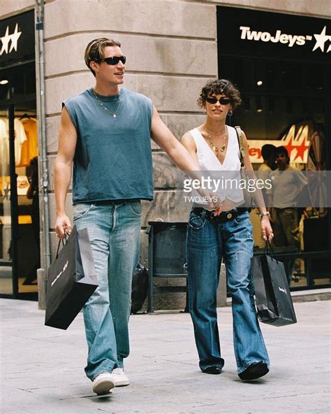 A Man And Woman Walking Down The Street Holding Hands