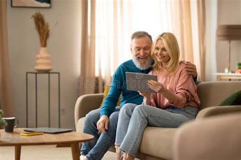 Cheerful Mature Couple Using Digital Tablet Relaxing Sitting At Home Stock Image Image Of
