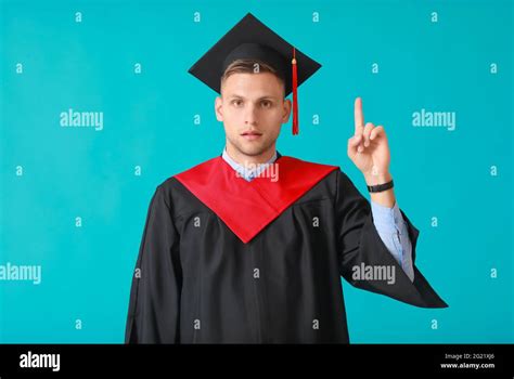 Male Graduating Student With Raised Index Finger On Color Background