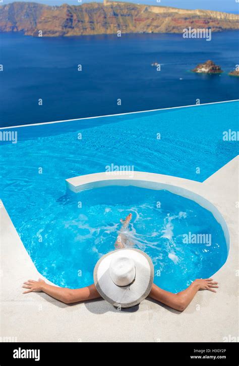 Woman Relaxing In Infinity Swimming Pool Looking At View Stock Photo