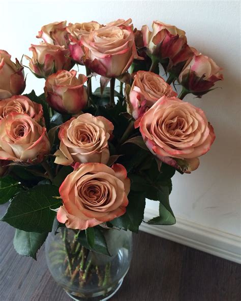 A Vase Filled With Pink Roses On Top Of A Wooden Table