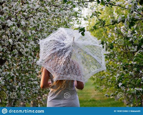 Girl With A White Umbrella In Blooming Apple Trees In The Garden Stock