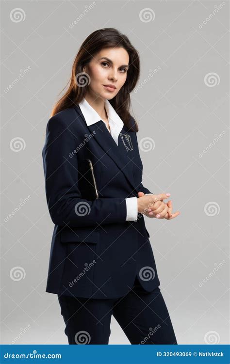 A Woman In A Business Suit Is Standing With Her Hands Folded Stock