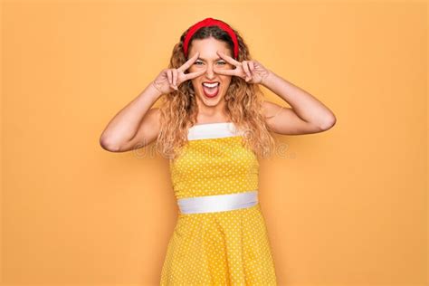 Belle Blonde Pinup Femme Aux Yeux Bleus Portant Le Diadem Debout Sur Fond Jaune Faisant Symbole