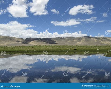 The Quiet And Beautiful Blue Lake At The Foot Of The Mountain Reflects