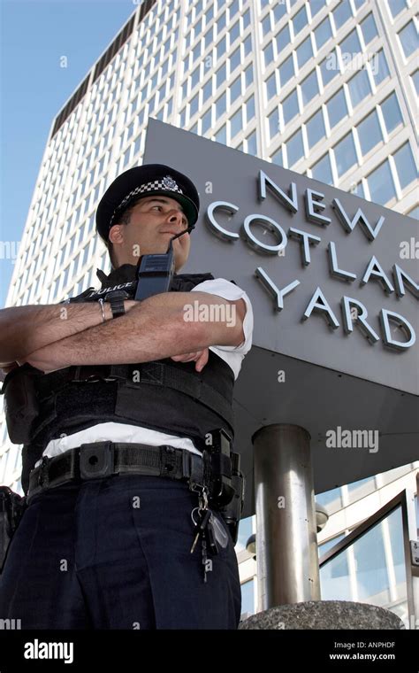 Policeman Officer Outside New Scotland Yard Building With Rotating Logo