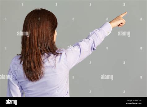 Back View Of A Business Woman Pointing Finger On Gray Background Stock