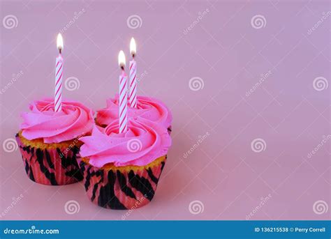 Three Cupcakes With Pink Frosting And A Single Candle On Each Stock