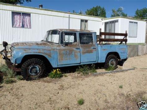 An Old Blue Truck Parked In Front Of A White Building With A Wooden