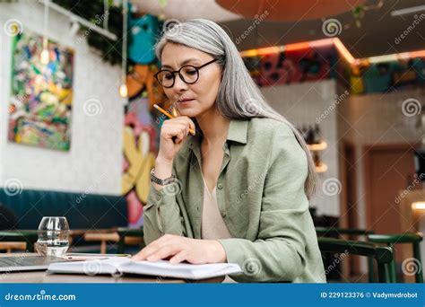 Mature Grey Thinking Woman Working With Planner In Cafe Stock Photo