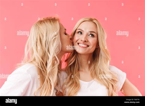 Pretty Blonde Woman Kissing Her Pretty Pleased Sister Which Looking Up And Enjoys Over Pink