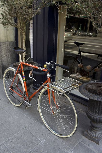 An Orange Bicycle Parked On The Side Of A Street Next To A Lamp Post