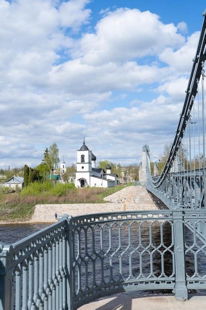 Puente de cadenas sobre el río Velikaya y iglesia de San Nicolás en el