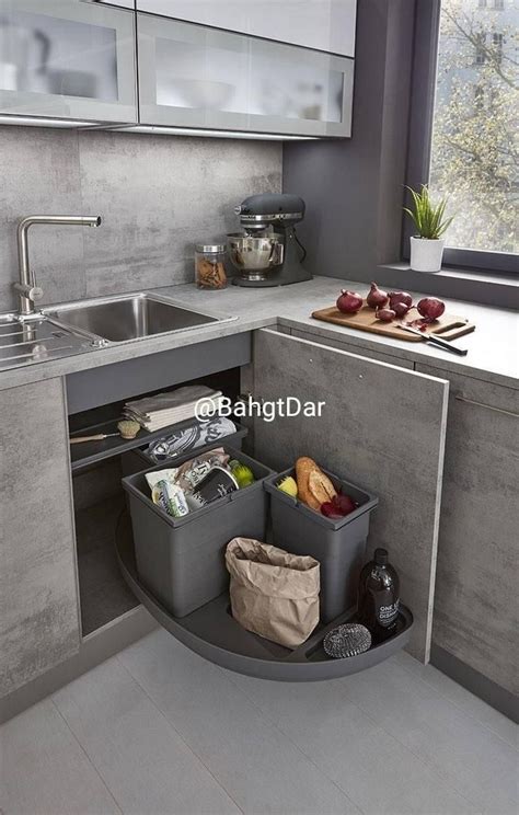 A Kitchen With A Sink Counter Top And Trash Cans In The Corner Next To It