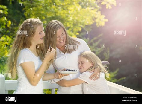 Mother And Daughters Enjoying The Summer Day On Outdoor Deck While