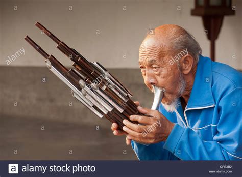 Chinese man playing a Sheng musical instrument or bamboo mouth organ ...