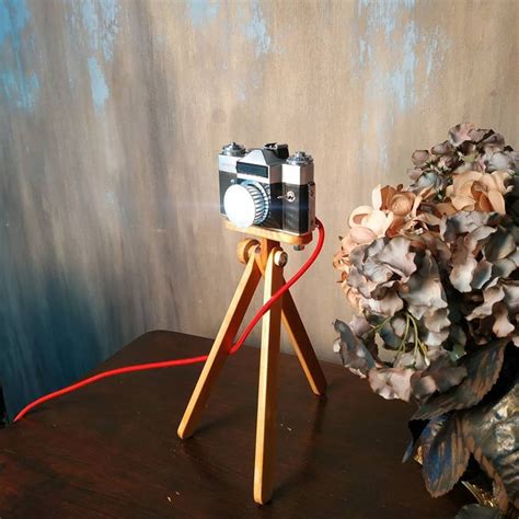 An Old Fashioned Camera On A Tripod Next To A Bouquet Of Flowers