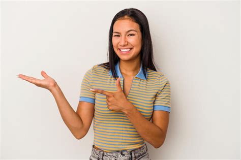 Jovem mulher latina isolada no fundo branco animada segurando um espaço de cópia na palma da mão