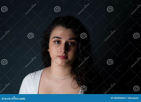 Young Woman With A Stoic Expression Stares Directly At The Camera Stock