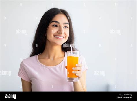 Cheerful Indian Woman Holding Glass Of Refreshing Fruit Juice Indoors