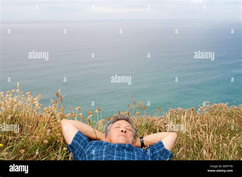 Mature Man Lying Down On The Grass At The Seaside Cornwall UK Stock Photo Alamy