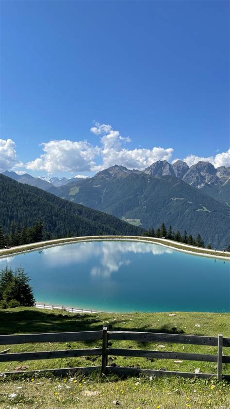 A Large Blue Lake Surrounded By Mountains In The Distance With A Wooden