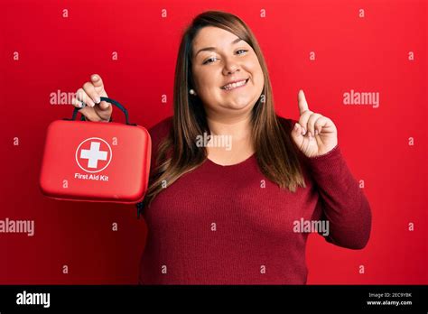 Beautiful Brunette Plus Size Woman Holding First Aid Kit Smiling With An Idea Or Question
