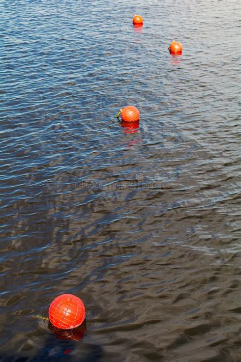 Four Bright Orange Buoys Floating On River Water Surface Stock Image