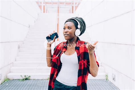 Young Black Woman Listening Music With Headphones And Smart Phone Hand