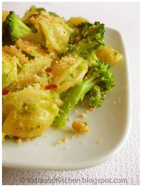 A White Plate Topped With Pasta And Broccoli Covered In Cheese Flecks