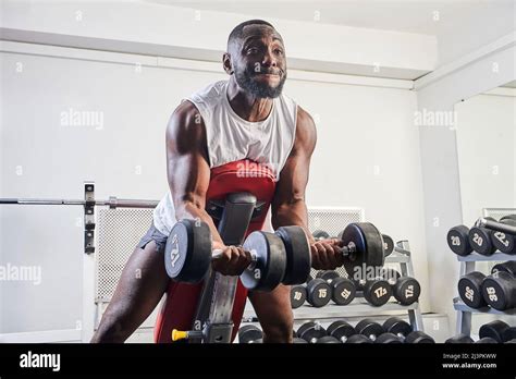 An African American Man Shakes His Biceps On An Inclined Bench In The