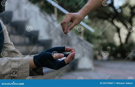 Woman Giving Money To Homeless Beggar Man Sitting In City Stock Image