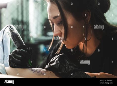 A Professional Tattoo Artist Makes A Black And White Tattoo On A Woman