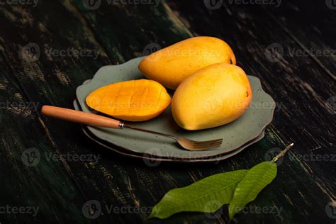 Cut And Complete Mangoes On A Plate In A Dark Environment Stock