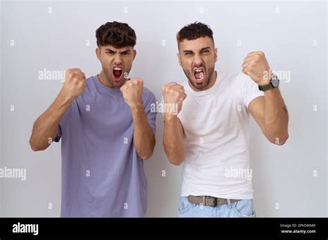 Homosexual Gay Couple Standing Over White Background Angry And Mad Raising Fists Frustrated And
