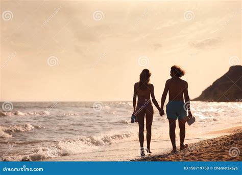 Mujer Joven En Bikini Y Su Novio Caminando En La Playa Al Atardecer Foto De Archivo Imagen De