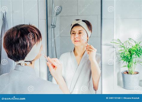 Woman In Bathrobe And Hair Band Looking In The Mirror And Making Face