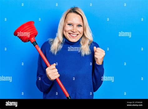 Beautiful Caucasian Blonde Woman Holding Toilet Plunger Screaming Proud