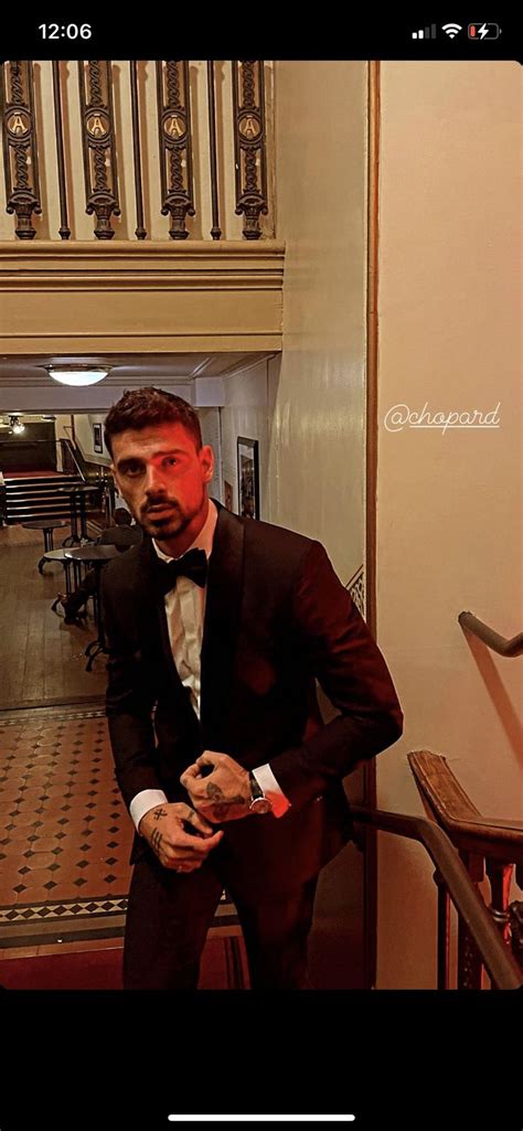 A Man In A Tuxedo Standing Next To A Stair Case And Looking At The Camera