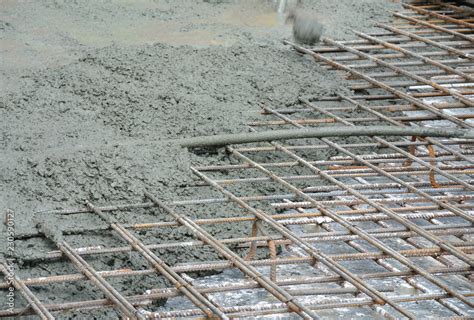 The wet concrete is poured on a steel reinforcement bar to form strong ...