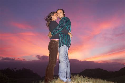 A couple hugs on top of a hill with a pink sunset behind them Free ...