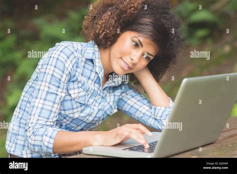 Gorgeous Happy Brunette Sitting At Picnic Table With Laptop Stock Photo