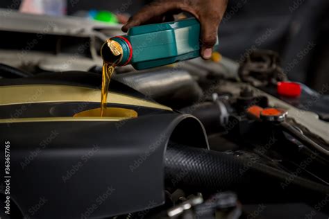 Car Mechanic Replacing And Pouring Fresh Oil Into Engine At Maintenance