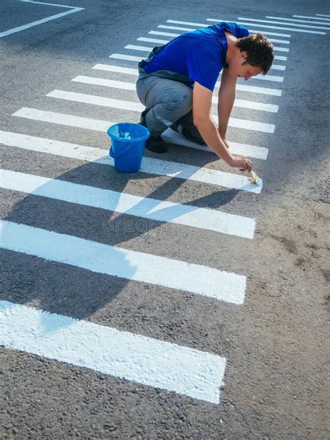 Road Service Worker Sits On His Lap And Paints Striped Pedestrian
