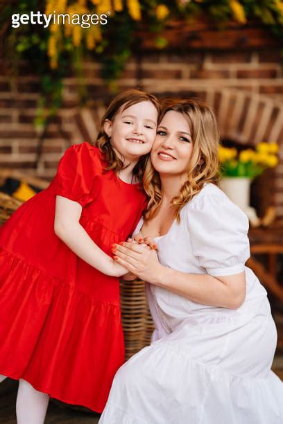 Mother And Daughter Cuddling In A Room By The Fireplace In Elegant